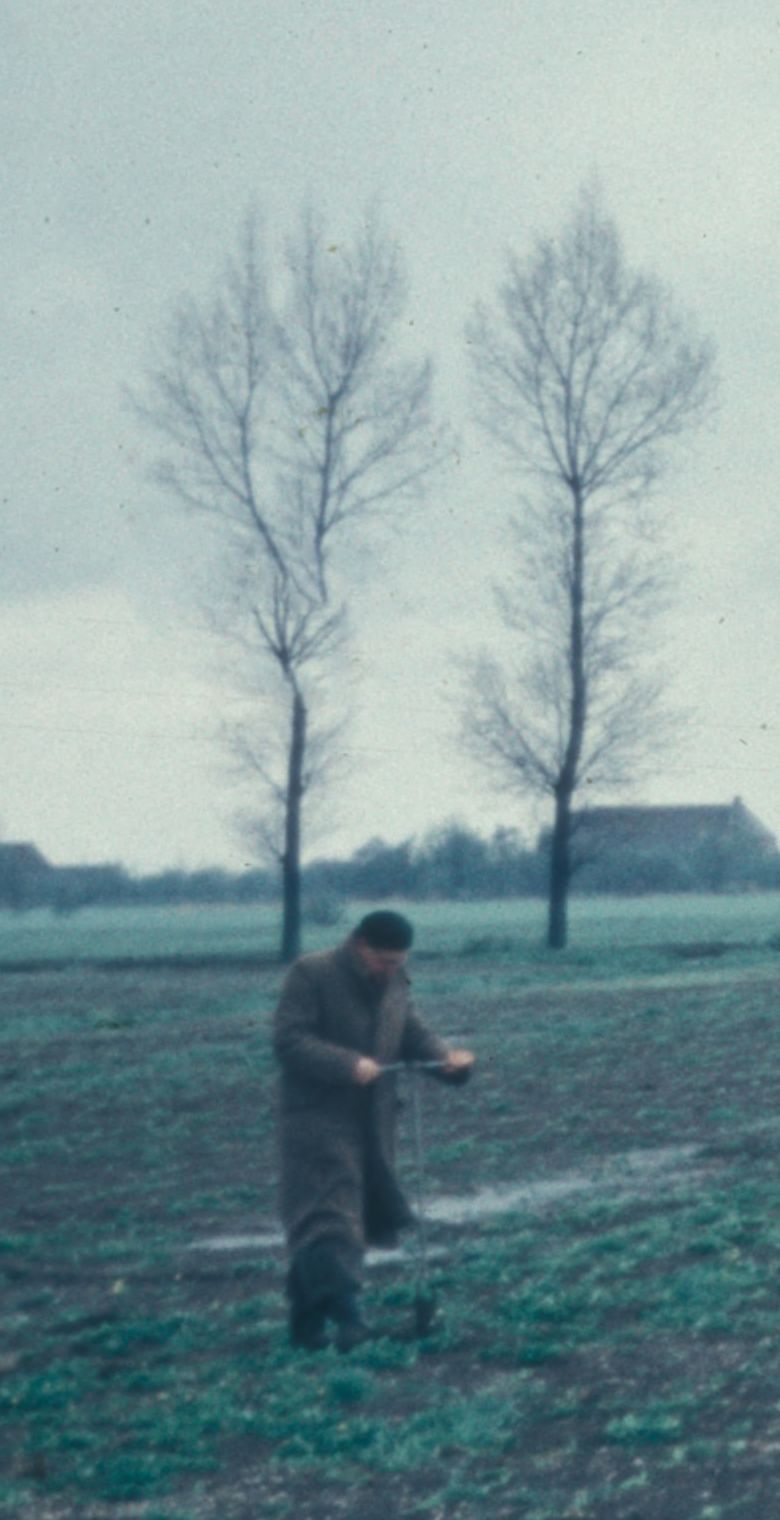 Een man met een grond- of edelmanboor op een akker